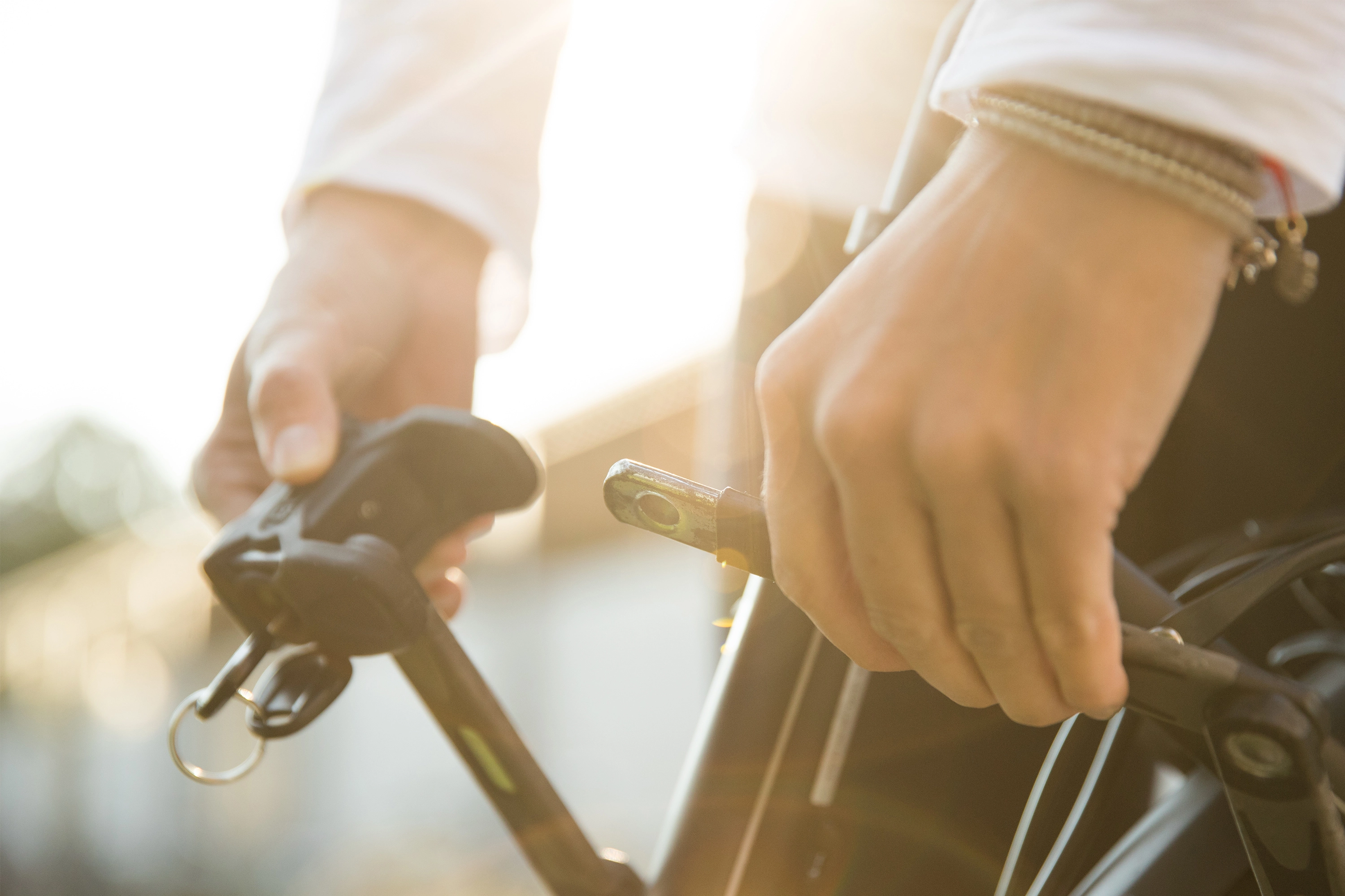 Eine Detailaufnahme eines Radfahrers, der sein Fahrradschloss schließt Eine Detailaufnahme eines Radfahrers, der sein Fahrradschloss schließt
